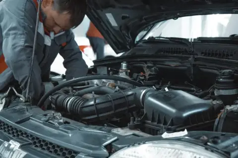 Mechanik pracuje przy silniku samochodu, sprawdzając, ile kosztuje wymiana oleju.