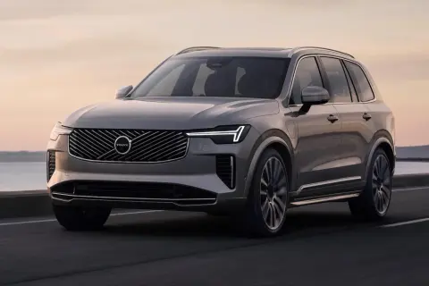Elegancki, szary Volvo XC90 T8 sunie po drodze przy zachodzie słońca.
