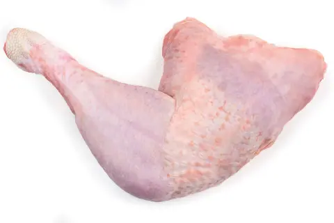Una zampa di tacchino cruda, con la pelle rosata e squamosa alla fine, pronta per essere cucinata.