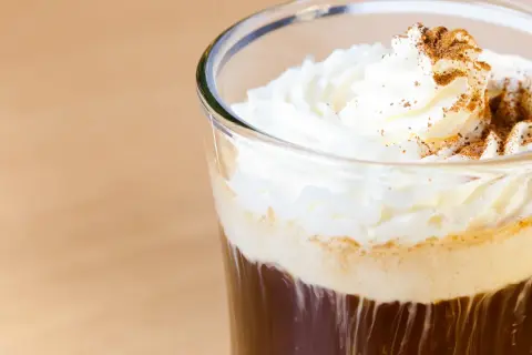 Ein erfrischender Eiskaffee mit Sahne und Zimt bestreut, perfekt für einen warmen Tag.