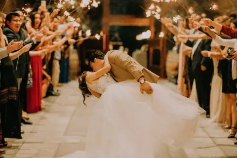 Coppia si bacia tra scintille di bengala, circondata da invitati festanti. Un momento magico, come i migliori giochi matrimonio.