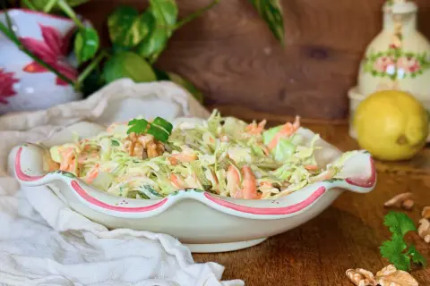 Deliciosa ensalada de col cremosa con zanahoria rallada, coronada con nueces y perejil. Perfecta para acompañar cualquier comida.
