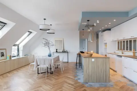 Un espace de vie lumineux avec carrelage cuisine ouverte et parquet salon en chevrons. Une table à manger est dressée, prête pour un repas convivial.