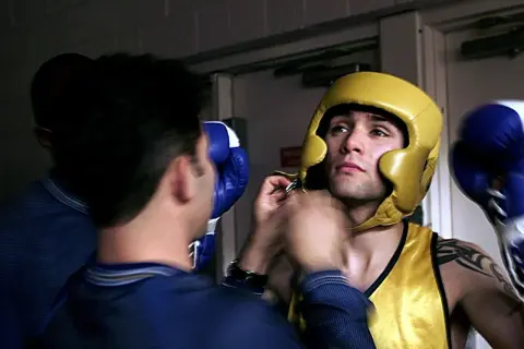 A boxer in a yellow headguard and vest gets ready for the fight, wondering how many rounds in boxing he'll endure.