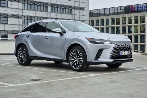Srebrny Lexus RX350h zaparkowany przed nowoczesnym budynkiem biurowym.