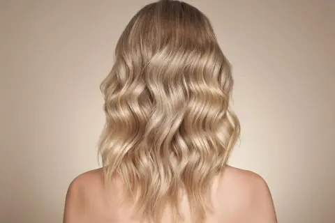 Piękne, falowane beżowe blond włosy opadające na ramiona.