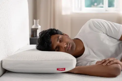 A man sleeps soundly on a white pillow, enjoying a peaceful rest. This image reassures that bamboo pillows are not toxic.