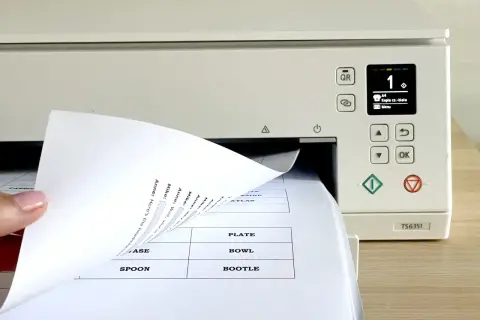 Dłoń wsuwa papier do drukarki, na ekranie widoczny numer 1 i opcja "Kopia cz.-biała".
