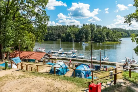 Namioty rozbite nad jeziorem, gdzie cumują żaglówki. Idealne miejsce na wypoczynek, prawdziwy pole namiotowe Mazury.