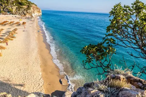 Piękna plaża w Albanii z turkusową wodą i rzędami parasoli. Ceny wakacji w Albanii są przystępne, a widoki zachwycające.
