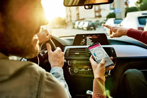 Kierowca i pasażerka sprawdzają nawigację w telefonie, ustalając trasę i czas podróży.