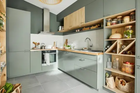 Moderna cocina verde y madera con estanterías abiertas llenas de botellas, cestas y tarros.