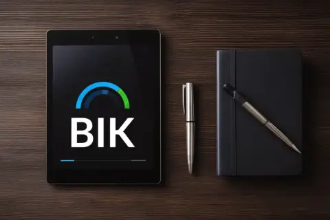 Tablet z logo BIK, długopis i czarny notatnik na drewnianym tle.