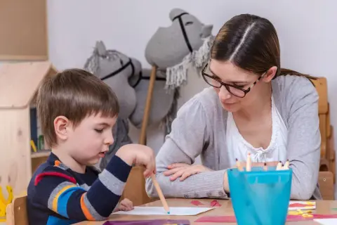 Nauczycielka wspiera chłopca z zespołem Aspergera w rysowaniu. Skupienie na zadaniu, a nie na tym, jak karać dziecko z zespołem Aspergera.