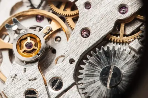 Detalle de un mecanismo de reloj, mostrando engranajes y el volante, que es un oscilador, en su interior.
