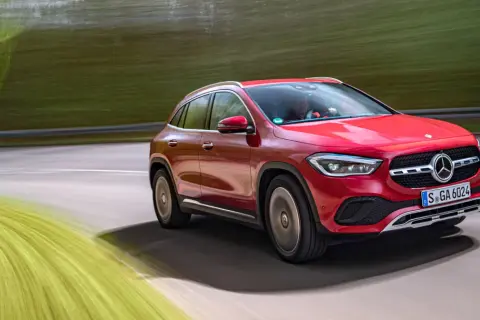 Röd Mercedes GLA på en testkörning längs en grönskande väg.