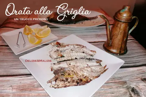 Orata alla griglia succulenta, servita con spicchi di limone e un'antica oliera in rame. Un vero tesoro culinario.