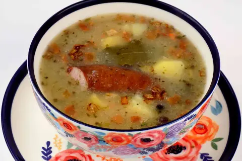 Jak zrobic zalewajke? Aromatyczna zupa z kiełbasą, ziemniakami i majerankiem w ozdobnej miseczce.
