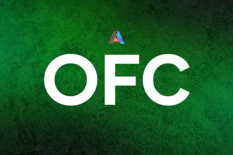 Letras blancas "OFC" sobre fondo verde texturizado. Un pequeño logo triangular con los colores de la bandera de Ghana aparece sobre la "F".