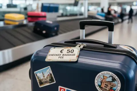 Bagaż rejestrowany kosztuje 50 euro. Na walizce widać etykietę z tą informacją i naklejki z podróży.