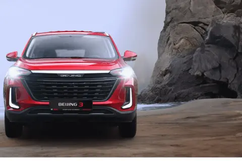 Czerwony BAIC Beijing 3 na tle skalistej plaży.