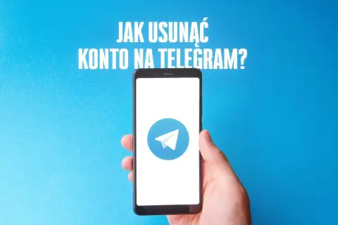 Dłoń trzyma smartfon z logo Telegram na niebieskim tle.