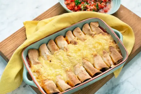 Enchiladas kyckling i ugnsform, gyllene och gratinerade med ost. Serveras med en fräsch tomatsalsa.