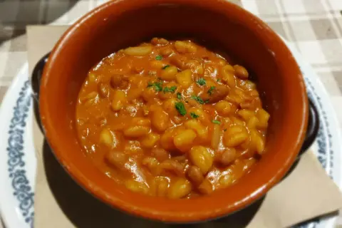 Fagioli in umido, un classico per scoprire cosa mangiare a Piacenza. Serviti in una ciotola di terracotta, sono un piatto saporito e confortante.