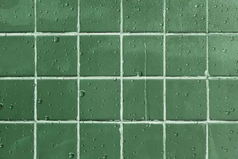 Gouttes d'eau sur un carrelage vert, montrant l'efficacité d'un traitement pour imperméabiliser un carrelage poreux.