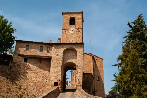 Porta Urbica a Montefeltro: un arco in mattoni con torre dell'orologio, ideale per scoprire cosa vedere in questo borgo storico.