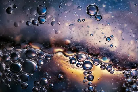 Close-up of oil and water bubbles with iridescent colors and reflections.