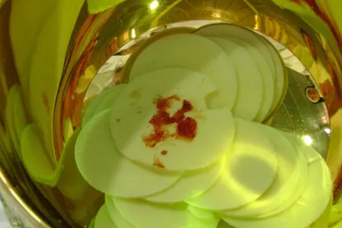 Hostie z plamą krwi, symbolizujące cud eucharystyczny w Indiach, w złotym naczyniu.
