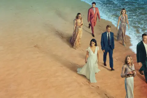En grupp människor i eleganta kläder går längs en strand. Kanske är de det perfekta paret, eller så döljer de mörka hemligheter.