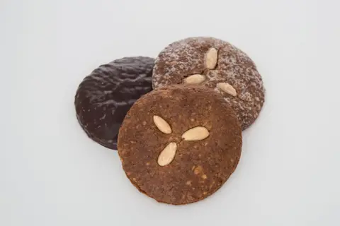 Drei runde Elisenlebkuchen, einer schokoladenüberzogen, die anderen mit Mandeln verziert. Beste Elisenlebkuchen für den Genuss.