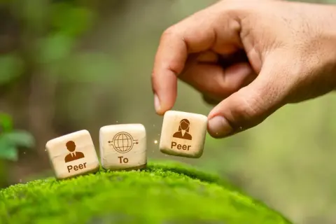 Dłoń układa kostki symbolizujące p2p: "Peer To Peer".