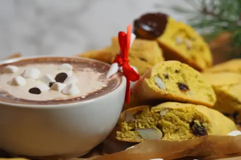 En kopp varm choklad med marshmallows och saffransbiscotti med mandel, perfekt för en mysig stund.
