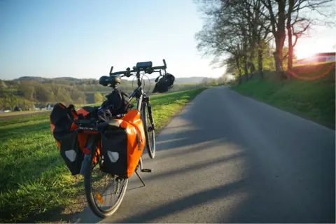 Rower z sakwami na drodze, idealny na długą podróż. Jak nie zasnąć w trasie? Wystarczy piękny widok i cel!