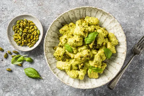 Gnocchis crémeux enrobés d'une sauce pesto onctueuse, parsemés de pistaches concassées et décorés de feuilles de basilic frais. Un délice !