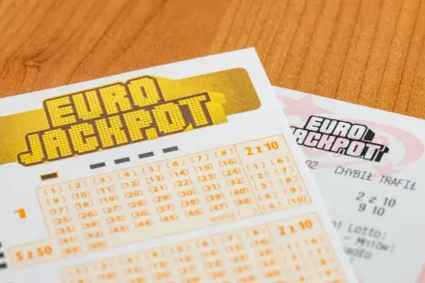 Kupony gry Eurojackpot z zaznaczonymi liczbami na drewnianym tle.