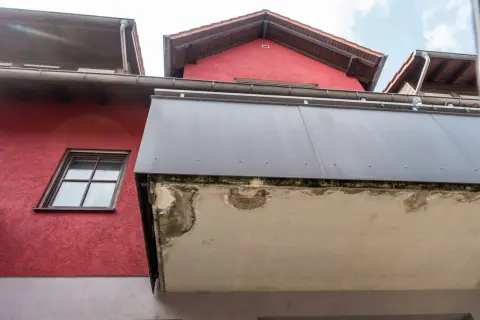 Betonplatte eines Balkons zeigt deutliche Schäden, die auf eine notwendige Sanierung hindeuten.