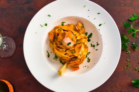 Pasta mit Lachs in cremiger Sauce, garniert mit Petersilie und Zitrone.