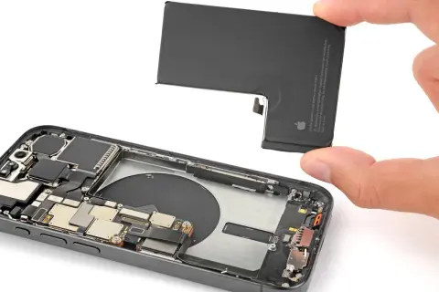 Wymiana baterii iPhone 13 Pro. Dłoń wyjmuje starą baterię z wnętrza telefonu.