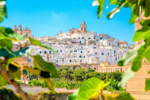 Weißes Dorf in Apulien, Italien, mit Blick auf grüne Bäume. Entdecken Sie Brindisi Geheimtipps für Ihren Urlaub.