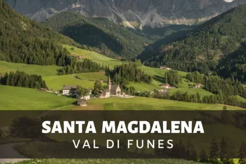Malownicze **Val di Funes** z kościołem i domami w dolinie, otoczone zielonymi wzgórzami i skalistymi szczytami Dolomitów.