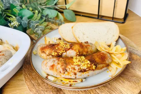 Pyszna, pieczona kiełbasa biała z musztardą i cebulką, podana z chlebem. Idealna na obiad.