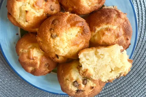 Saftige apfel muffins mit Schokoladenstückchen auf einem blauen Teller. Einer ist zerbrochen und zeigt das weiche Innere.