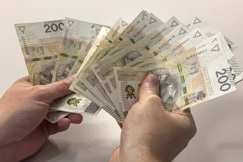 Dłonie trzymają plik banknotów 200 zł. Zastanawiasz się, czy alimenty można odliczyć od podatku?