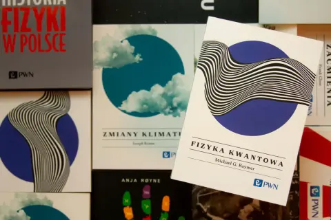 Książki o fizyce kwantowej i historii fizyki w Polsce. Jedna z nich, "Fizyka kwantowa" Michaela G. Raymera, leży na wierzchu.