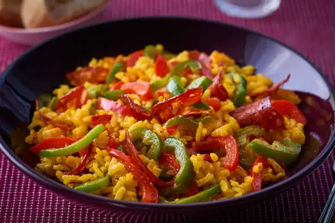 Un plat appétissant de riz à l'espagnol, garni de poivrons rouges et verts, et de chorizo.