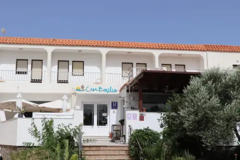 Casa Emilio Los Escullos, un hotel blanco con tejas rojas, balcón y vegetación exuberante.